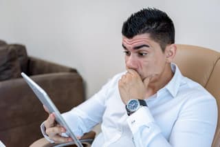 A man reading on his tablet. He has a concerned expression.

