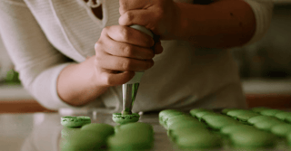 A person putting cream into a macaroon