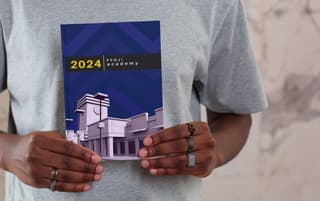 Man holding a 2024 Penji academy yearbook